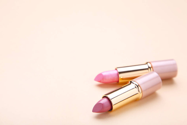 Two lipsticks on beige background. Cosmetic - Fotoğraf, Görsel