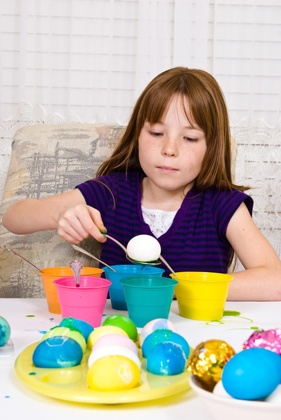 jong meisje in het proces van Pasen eieren beginnen te verlagen van een ei in de kleurstof kleuren - Foto, afbeelding