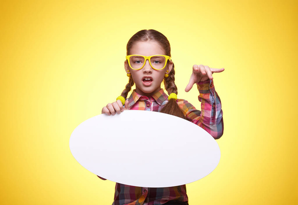 Έφηβο κορίτσι με μια αφίσα για κείμενο, αναιδής έκφραση του προσώπου, τα συναισθήματα των παιδιών, κορίτσι με τα γυαλιά, φωτεινό καρώ πουκάμισο, όμορφη νεαρή κοπέλα, πορτρέτο ενός νεαρού κοριτσιού - Φωτογραφία, εικόνα