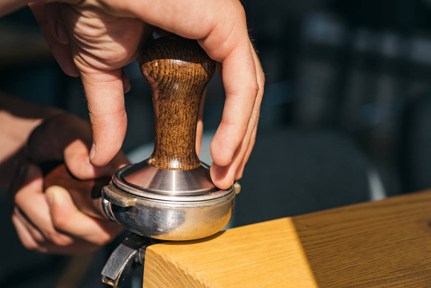 The perfect coffee that suits to your taste. Barista press coffee with tamper in portafilter. Brewing coffee equipment. Barista brew espresso drink in cafe. Coffee making in coffeehouse - Foto, Imagem