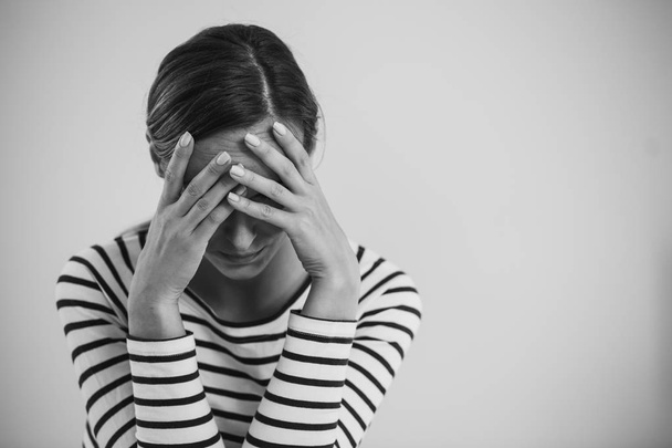Black and white photo of young hopeless woman suffering from depression and holding her head, photo with copy space - Foto, Bild
