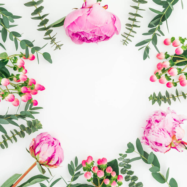 Floral frame van roze pioenrozen bloemen, hypericum en eucalyptus takken op witte achtergrond. Plat lag, top uitzicht - Foto, afbeelding