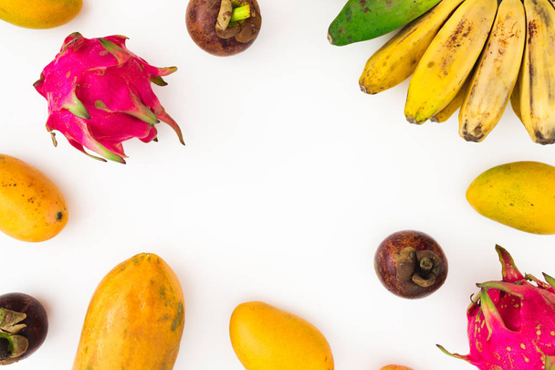 Obstrahmen aus Banane, Papaya, Mango mit Mangostan und Drachenfrüchten auf weißem Hintergrund. flach lag. Ansicht von oben. Tropenfruchtkonzept - Foto, Bild