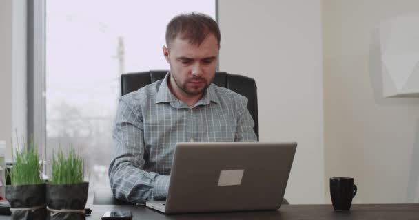 Concentrated office worker sitting on his work place and working on his laptop , panoramic office view. - Materiał filmowy, wideo