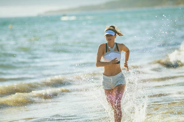 femme en bonne santé jogger en vêtements de sport sur la côte de l'océan dans la soirée de course. résistance à l'eau et au vent trouvée sur la côte océanique ouvrir de nouvelles façons d'entraîner votre corps. sportive défi corps entier
 - Photo, image