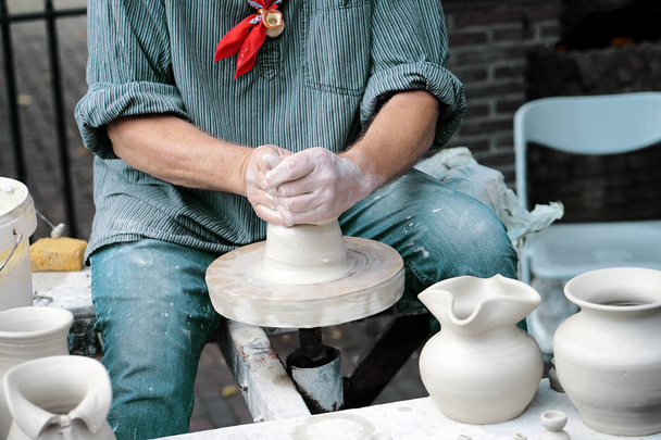 Hände in Großaufnahme, die Dosen oder Vasen aus grauem Ton herstellen. Menschenhände formen einen Tonkrug, Makro. Töpfer macht einen Krug. - Foto, Bild