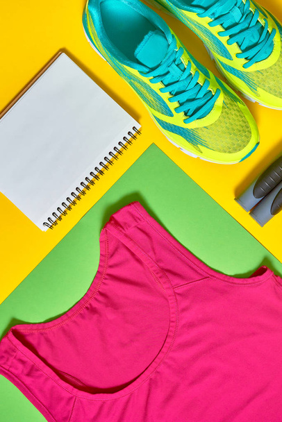 Sport shoes, woman's top bra, white blank notebook and skipping rope on colorful yellow and green backgroundon, copy space. Top view, flat lay. Sport and healthy lifestyle concept, flat lay - Fotoğraf, Görsel