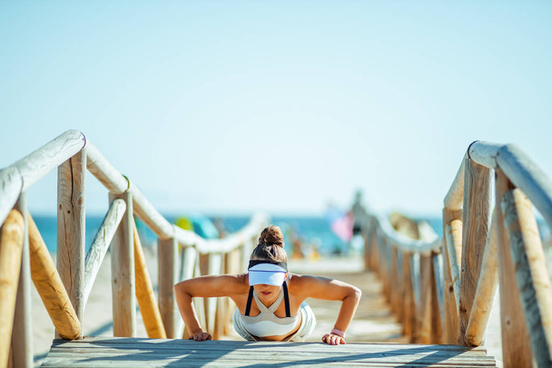 healthy sporty woman in sport clothes doing pushups on beach  - Foto, imagen