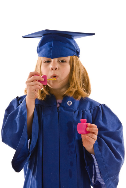 eine junge Absolventin in Mütze und Kleid bläst Blasen - Foto, Bild