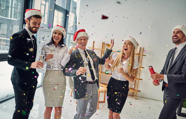 Merry Christmas and Happy New Year! Group of office workers celebrating winter holidays together at work. Business people drinking champagne in office. - Photo, Image