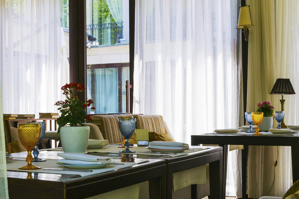 Modern Europees restaurant met houten tafel en multi-gekleurde sofa dicht bij raam. - Foto, afbeelding