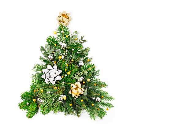 Christmas tree made of fir and pine branches with Christmas decorations on white background. Holiday concept. Flat lay, top view - Фото, изображение