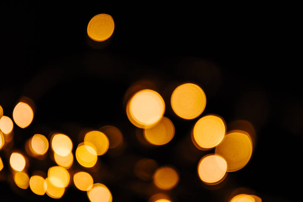 Abstract Gold bokeh sparkle on black background. Lights blurred bokeh  for christmas design - Photo, Image