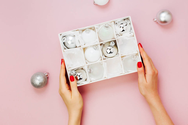 Female hands hold Stylish set of shiny silver christmas balls. Holiday concepts.  Flat lay, top view - Fotografie, Obrázek