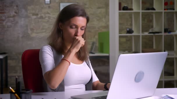 Attractive office worker typing on the laptop caughing feeling ill on the workplace indoors - Video