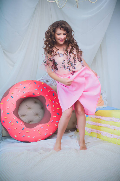 cute girl posing with pink donuts, fooling around, dessert, bad food, looks into the hole in the donut, keeps donuts by the eyes - Zdjęcie, obraz