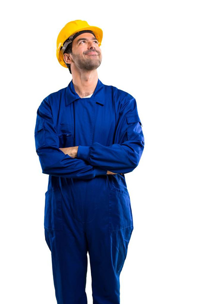 Young workman with helmet stand and looking up while smiling on isolated white background - Photo, image