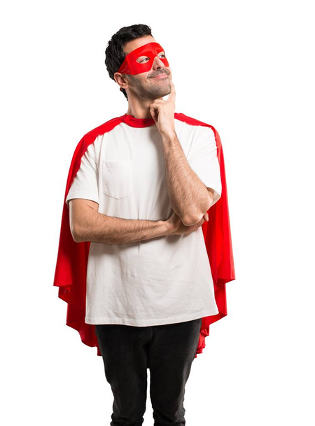 Superhero man with mask and red cape standing and thinking an idea while looking up on isolated white background - Foto, imagen