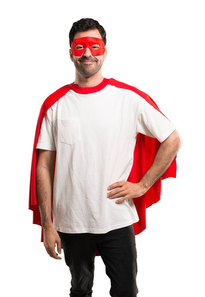 Супергерой в маске и красном плаще позирует с руками на бедре и улыбается на изолированном белом фоне
 - Фото, изображение