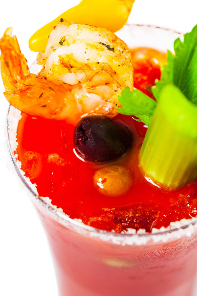 Cóctel Bloody Mary con vodka, zumo de tomate, salsa Tabasco y hielo decorado con apio y camarones aislados sobre fondo blanco. Enfoque selectivo
. - Foto, imagen