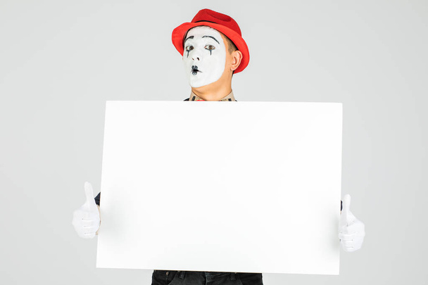 feliz artista MIME sosteniendo una pizarra blanca en blanco, sobre un fondo blanco - Foto, imagen