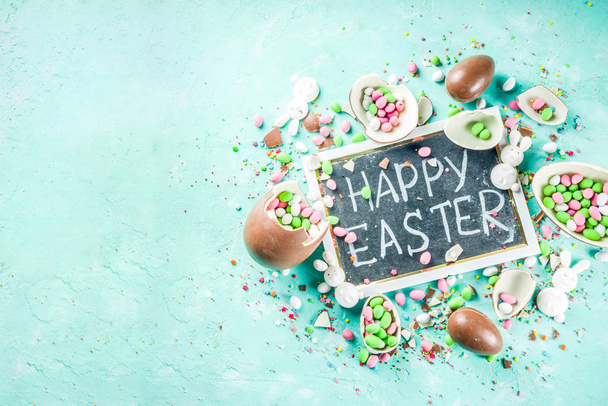 Colorful Wiosna Wielkanoc słodycze tło, czekoladowe jajka, cukier kropi i Zefir bunny, turkus jasnoniebieskie tło betonu kopia miejsce widok z góry - Zdjęcie, obraz