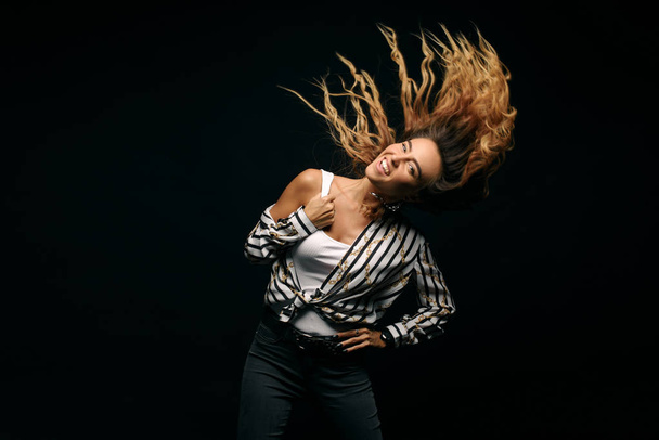 Portrait with copy space empty place of cheerful laughter funny comic girl having flying hair on black background, enjoying wind flow. Dancing for win on lottery  - Foto, imagen