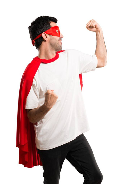 Супергерой в маске и красном плаще празднует победу в позиции победителя на изолированном белом фоне
 - Фото, изображение