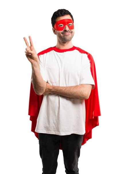 Superbohatera człowiek w Pelerynie maski i czerwony, uśmiechając się i pokazuje znak zwycięstwa z wesołą twarz na na białym tle - Zdjęcie, obraz