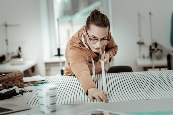 Young handsome designer in eyeglasses with long hair working with textile - Foto, Imagem