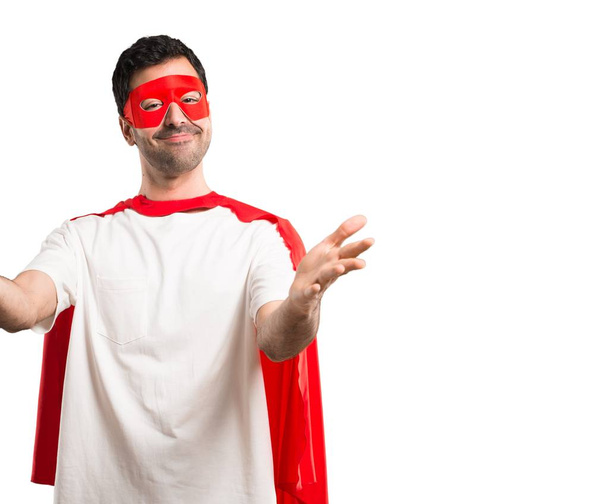 Uomo supereroe con maschera e mantello rosso che presenta e invita a venire con mano. Felice che tu sia venuto su uno sfondo bianco isolato
 - Foto, immagini