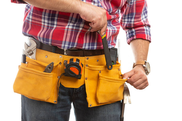 männliche Bauarbeiter Platzierung Schraubenschlüssel in Werkzeuggürteltasche an der Taille Nahaufnahme isoliert auf weißem Hintergrund - Foto, Bild