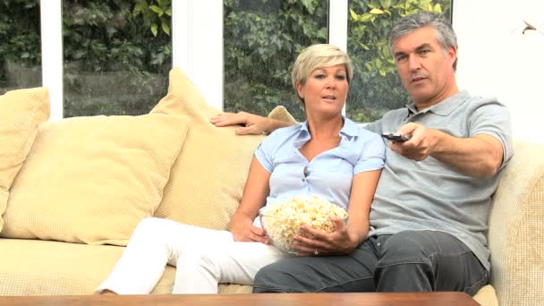 Atractiva pareja madura viendo televisión con palomitas de maíz
 - Imágenes, Vídeo