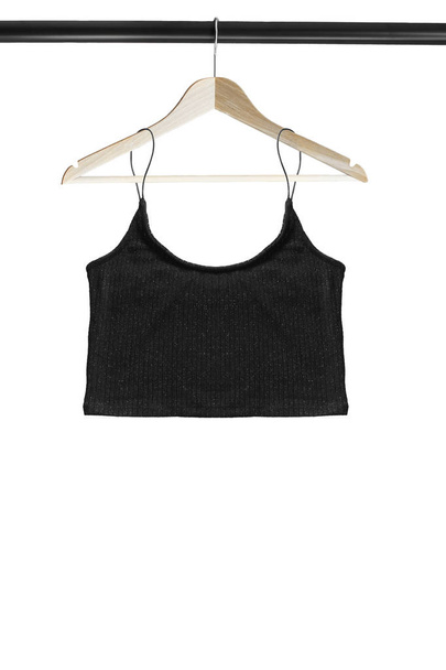 Black crop top hanging on wooden clothes rack isolated over white - Photo, image