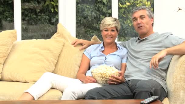 テレビの前でポップコーンを食べて成熟したカップル - 映像、動画
