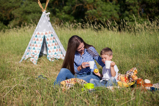 Mutter und kleiner Sohn essen im Picknickzelt - Foto, Bild
