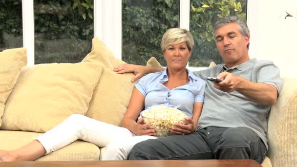 Ώριμη καυκάσιος ζευγάρι απολαμβάνοντας τηλεόραση & ποπ κορν - Πλάνα, βίντεο