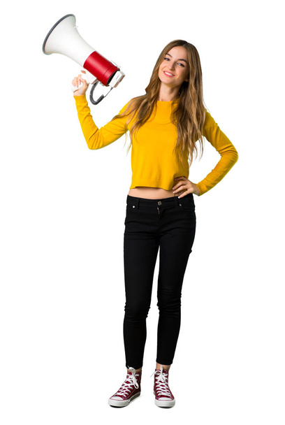 Pełnej długości strzał młodej dziewczyny z żółty sweterek gospodarstwa megafon na na białym tle - Zdjęcie, obraz