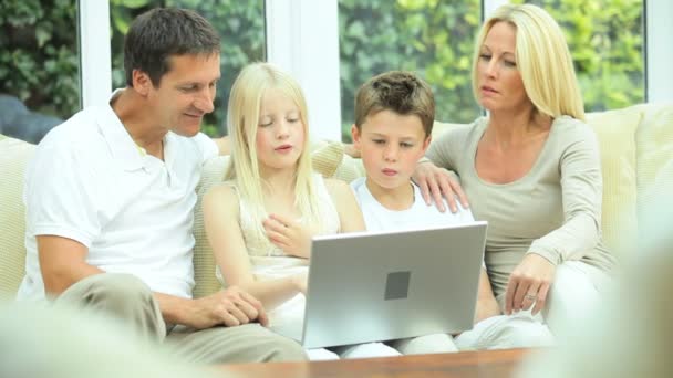 Familia joven caucásica usando el ordenador portátil en el sofá
 - Imágenes, Vídeo