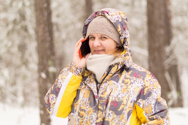 Uma mulher marca um número de telefone. Conversando com o uso da comunicação celular. Floresta de inverno nos arredores da cidade
. - Foto, Imagem