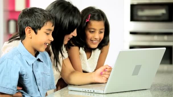 Young έθνικ μητέρα & παιδιών που χρησιμοποιούν φορητό υπολογιστή στην κουζίνα - Πλάνα, βίντεο