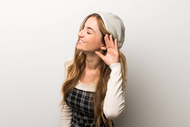 Fashionably woman wearing hat listening to something by putting hand on the ear - Zdjęcie, obraz