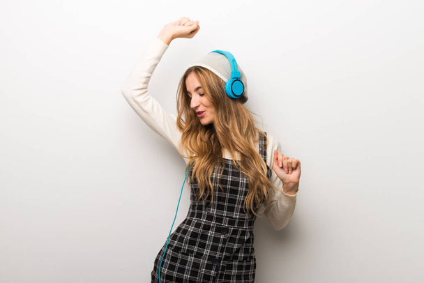 Mujer de moda con sombrero escuchando música con auriculares y bailando
 - Foto, Imagen