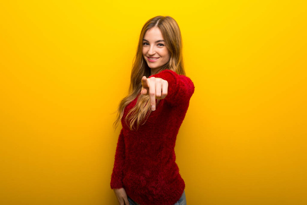 Jeune fille sur fond jaune vibrant pointe du doigt vers vous avec une expression confiante
 - Photo, image
