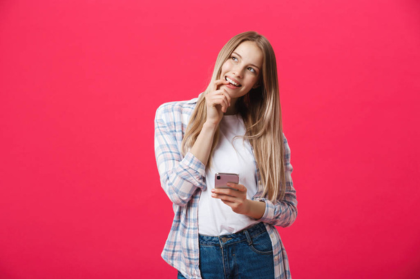 Smiling young woman thinking while using smartphone. - Photo, image