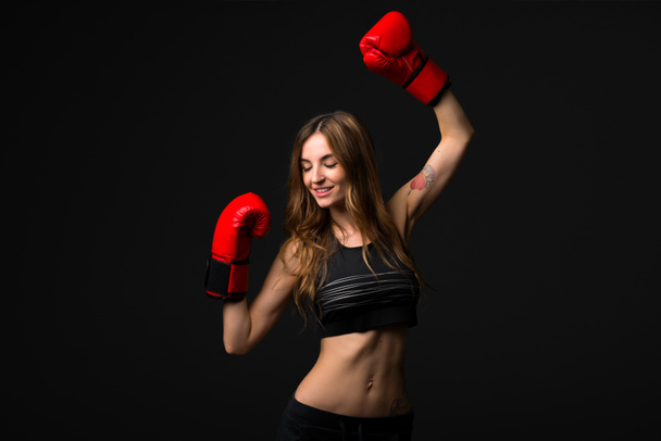 Mujer deportiva con guantes de boxeo sobre fondo oscuro
 - Foto, imagen
