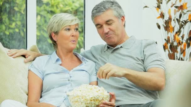 ώριμο ζευγάρι τρώγοντας ποπ κορν μπροστά από την τηλεόραση - Πλάνα, βίντεο