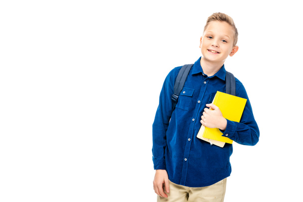 schoolboy in blue shirt with backpack holding books while looking at camera isolated on white - Φωτογραφία, εικόνα