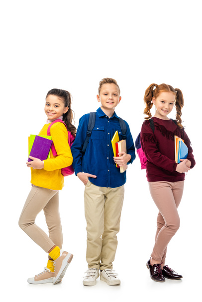 cute schoolchildren with backpacks holding books and smiling isolated on white - Foto, imagen