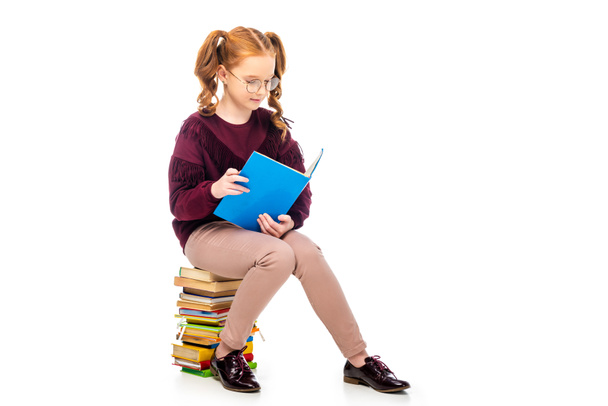 entzückendes Schulmädchen mit Brille liest Buch isoliert auf weiß - Foto, Bild
